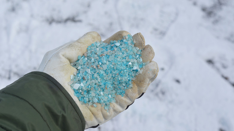 Hand spreading ice melt crystals to illustrate using tools and products that make shoveling easier