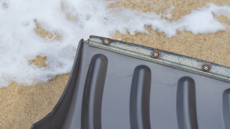 Close-up of a snow shovel with a worn metal edge showing why a dull blade reduces efficiency